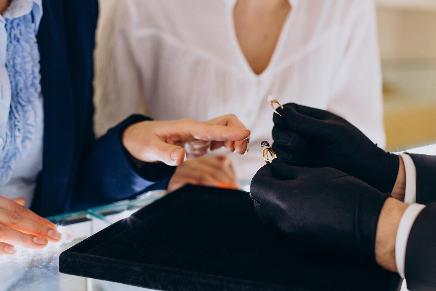 Person wearing black gloves holding a small object with another person's hand.