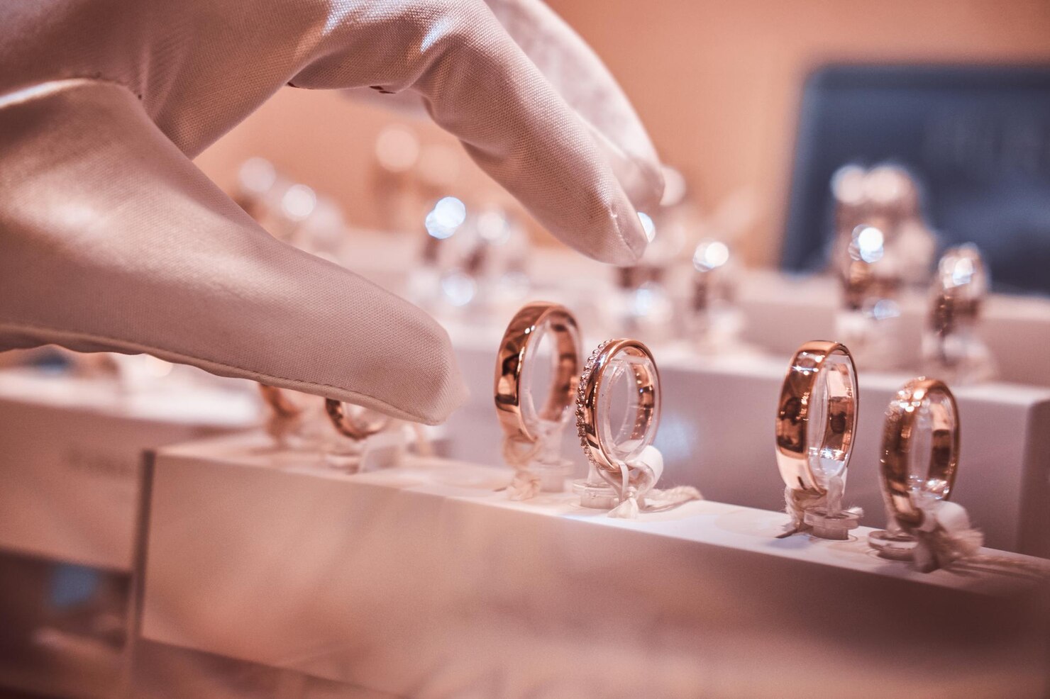 Rose gold rings on display with a hand reaching out to pick one up.